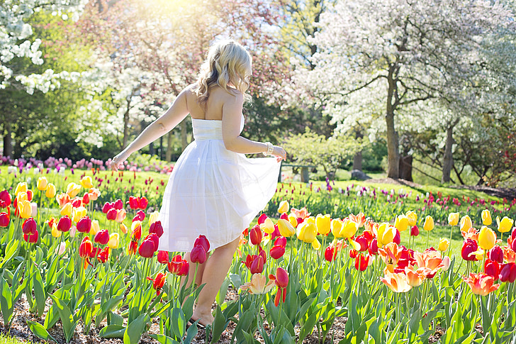 woman wearing white strapless dress standing on flower field during daytime