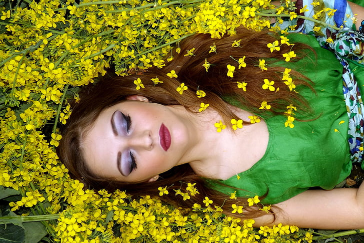 woman in green sleeveless top laying on yellow flowers