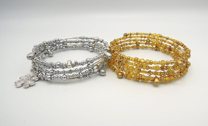 two beaded gray and beige bracelets on white surface