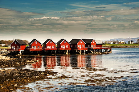 six red houses near body of water under blue cloudy sky