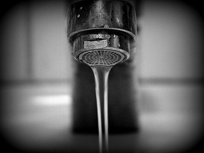 grayscale photography of opened faucet