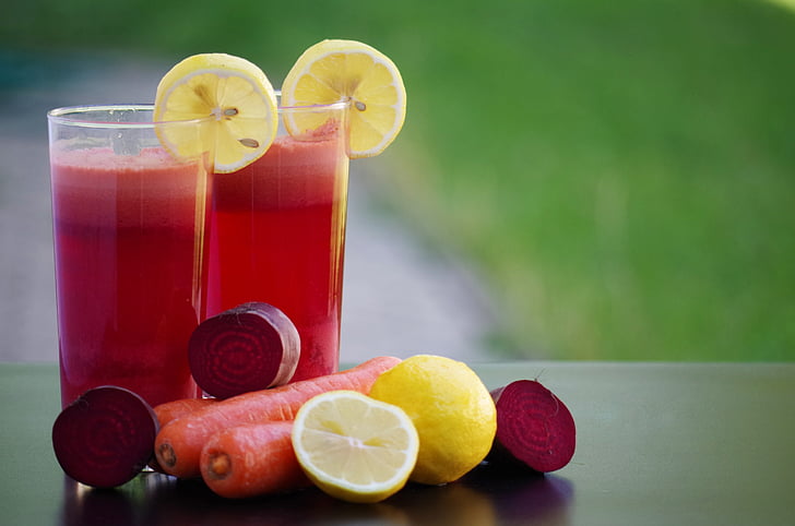 selective focus photography of two glass of juices with lemon and carrots