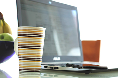 beige and black coffee mug near black ASUS laptop