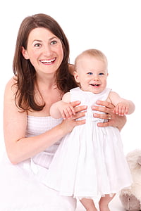woman wearing white dress carrying baby while smiling photo