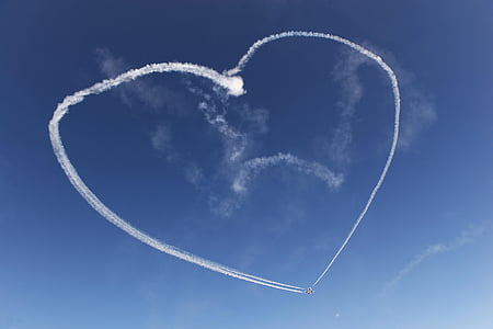 plane with smoke forming heart on sky