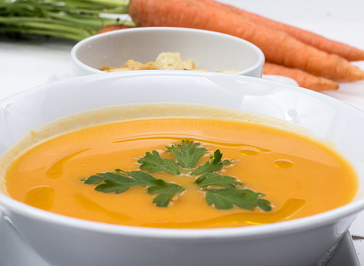 soup in white ceramic bowl beside carrots
