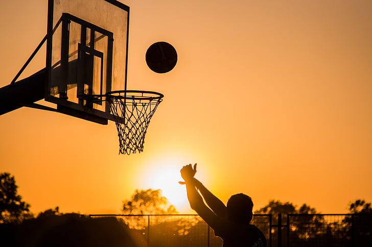 silhouette photo of a person playing a basketball