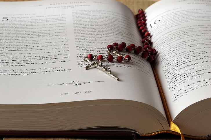 silver-colored rosary on bookpage