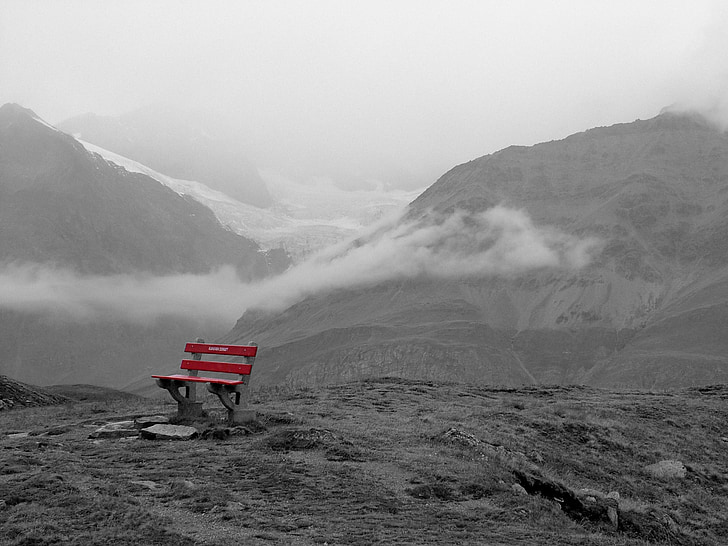 selective photography of red bench on the edge of mountain