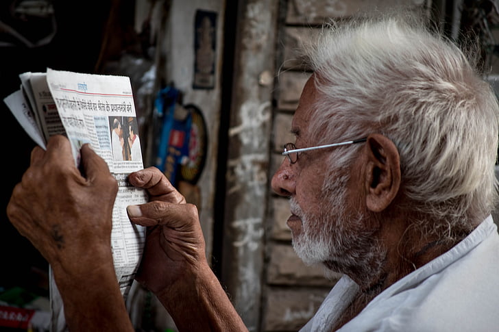 man reading a newspaper with his eyeglasses