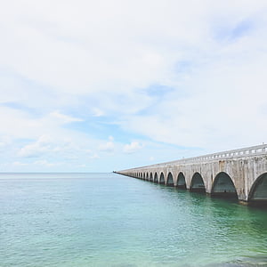 gray concrete bridge on ocean during daytime