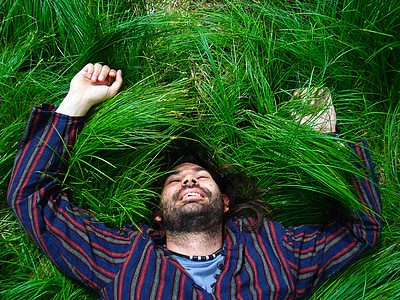 man in multicolored top lying on green grass field