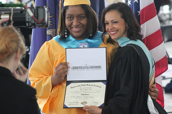 woman standing next to another woman holding diploma