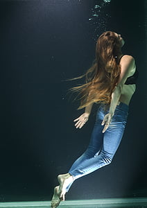 woman in blue-washed jeans and black brassiere swimming