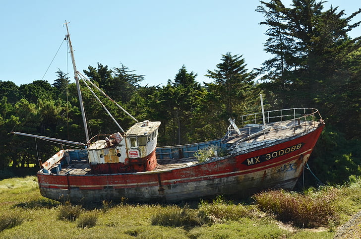 red and grey fishing boat on green grass field