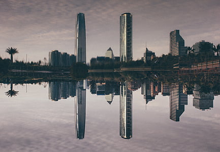 three high-rise buildings casting reflection on body of water during daytime