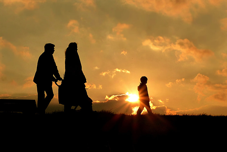 silhouette of man, woman, and child walking during sunrise