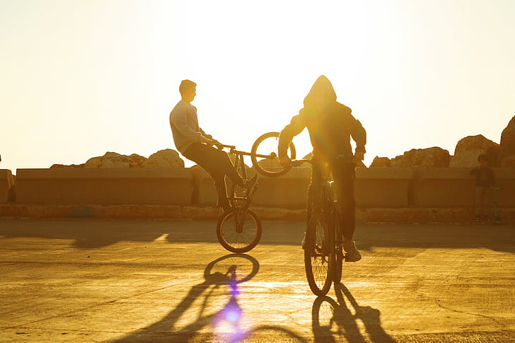 two person riding a bicycle doing tricks