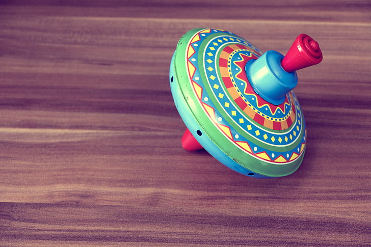 multicolored plastic spinning top toy on wooden surface