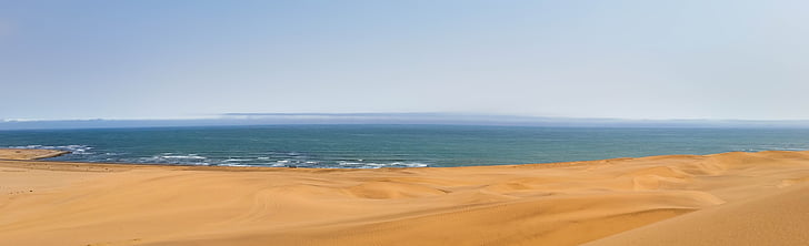 brown sand and body of water photography