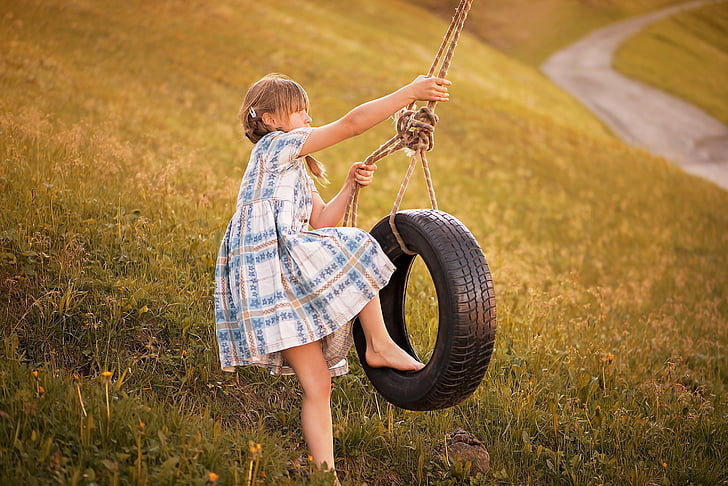 girl about to ride a swing vehicle tire at the green grass field
