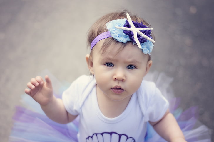 baby in white and purple tutu dress shallow focus photo