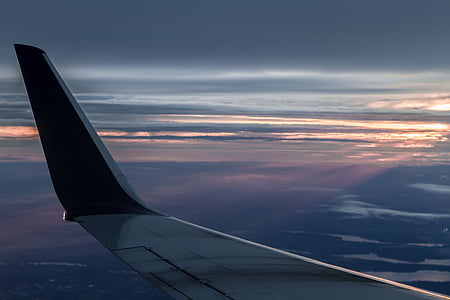 black and gray airplane wing with view of cloudy horizon