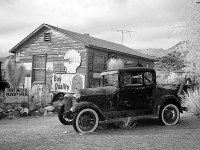 grayscale photography of vintage car near building