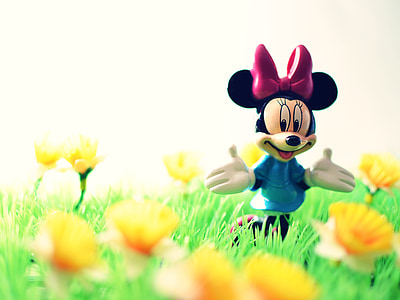 shallow focus photography of Minnie Mouse figure surrounded by yellow flowers