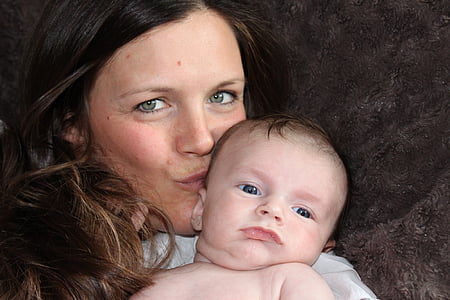 woman with brown hair carrying a baby