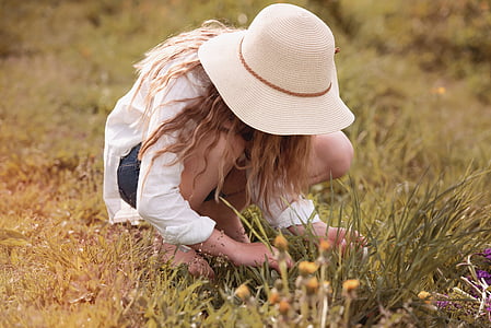 woman with sunhat picking flowers on field