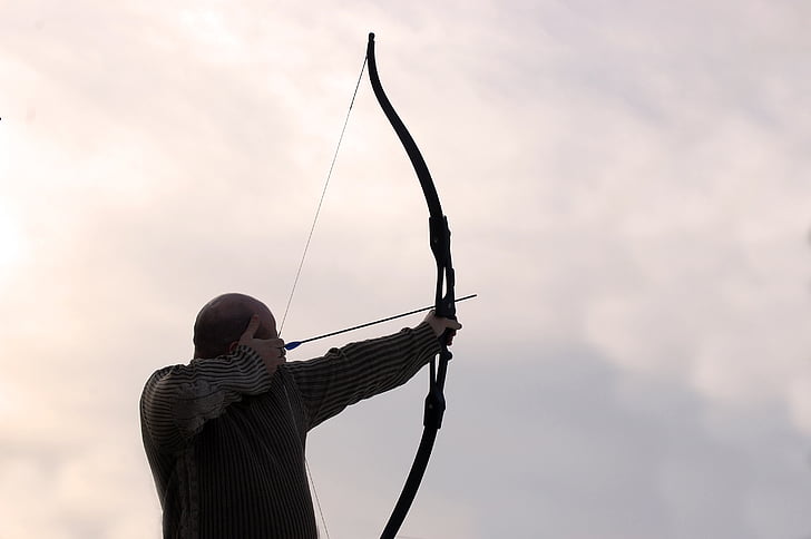 person wearing black long-sleeve top holding long bow