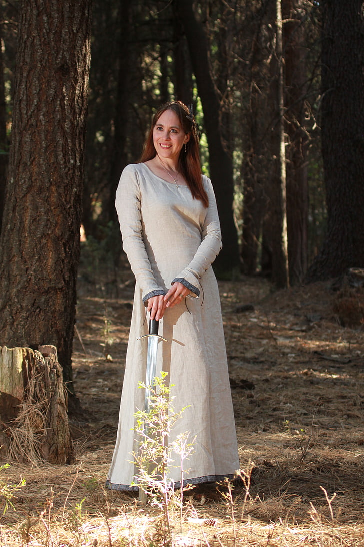 woman in grey scoop-neck long-sleeved dress holding sword while smiling