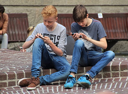 two men wearing blue denim jeans sitting on concrete floor