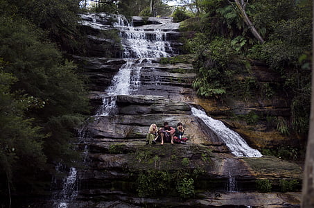 three people sitting near waterfalls