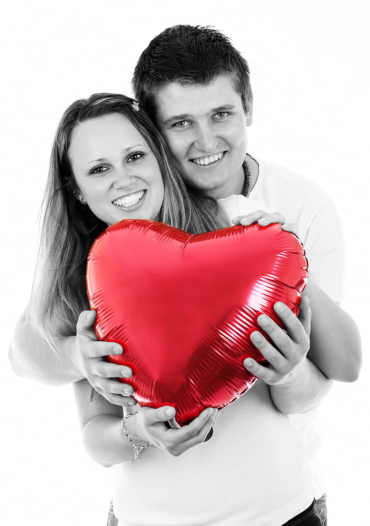 selective color photo of couple holding red heart balloon