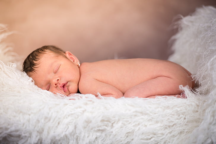 baby sleeping on white textile