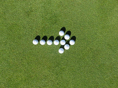white golf balls forming arrow on green grass