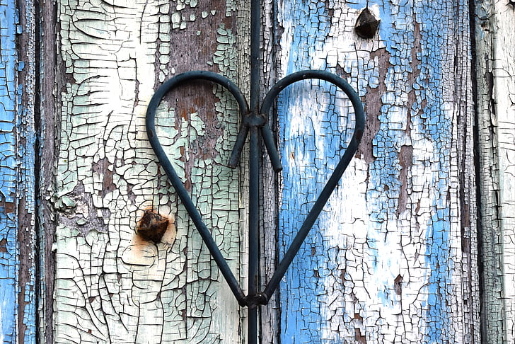 black wrought iron heart on white and blue wooden surface