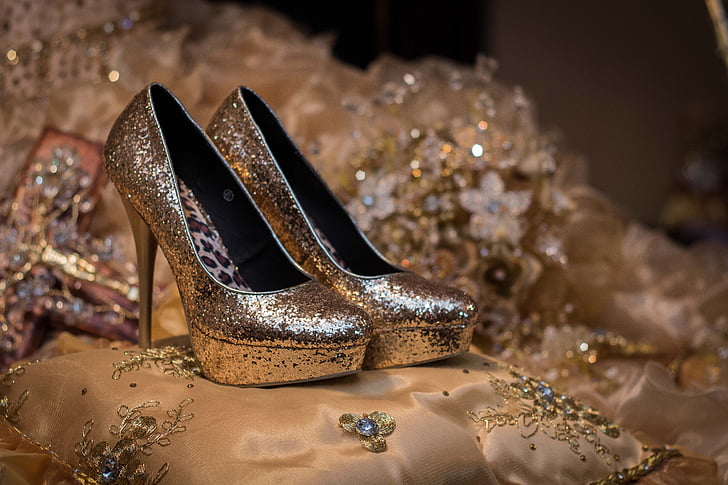 pair of gold glitter-type platform pumps on bed