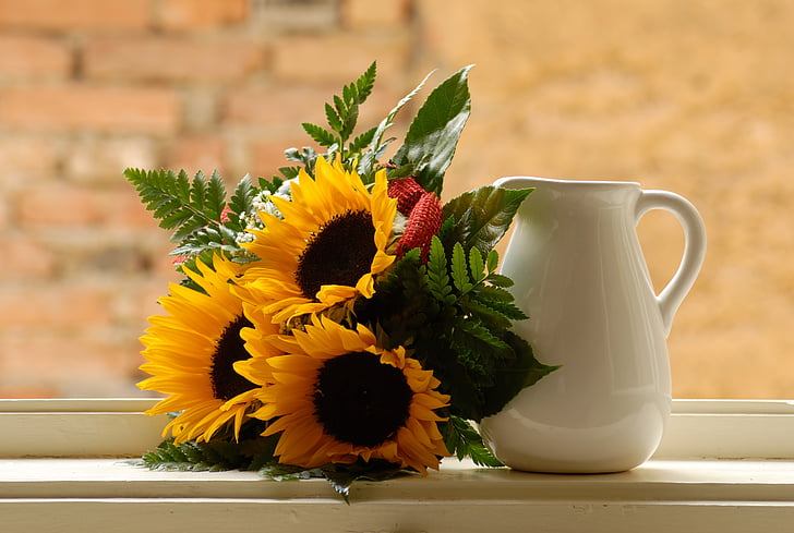 yellow sunflower bouquet beside white ceramic pitcher