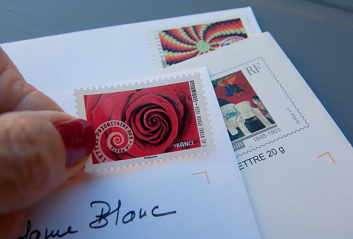 person holding red and white postage stamp