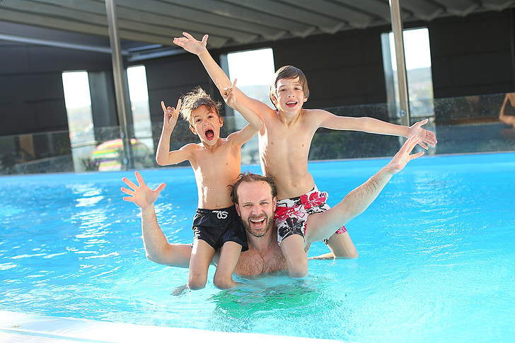 man with children swimming in the pool
