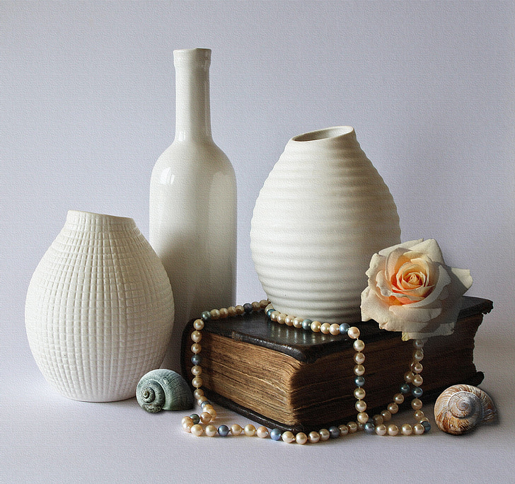 three white ceramic vases and brown book