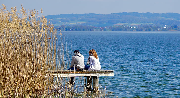 man and woman sitting on brown wooden boardwalk