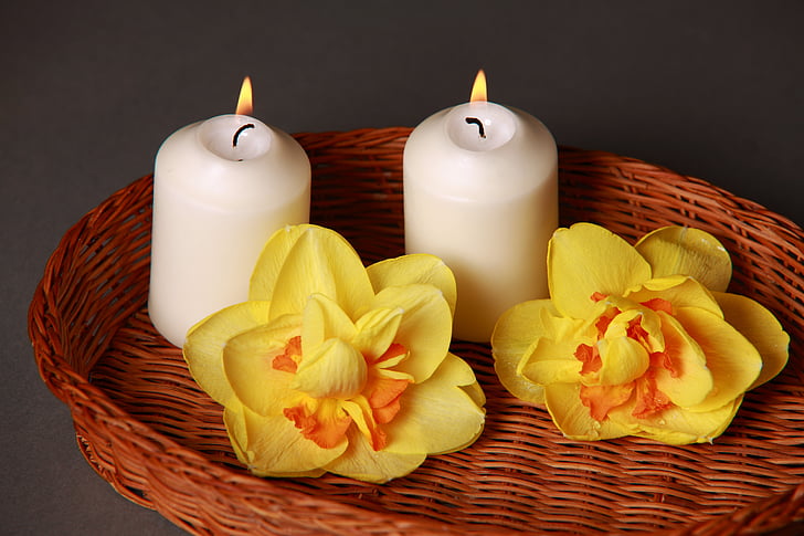 two lighted white pillar candles on brown woven basket