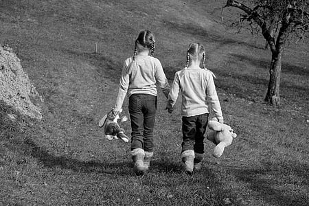 gray scale photo of two girls holding hands holding plush toys