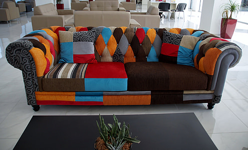 photo of empty tufted gray and multicolored roll-arm sofa