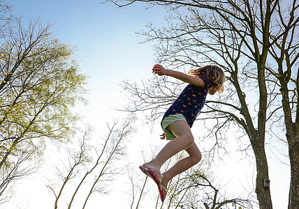 girl jumping near trees