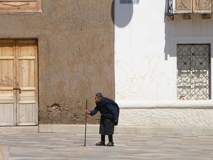person walking on street while holding walking cane